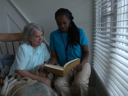 An image of a Home Health Aid Reading to Patient